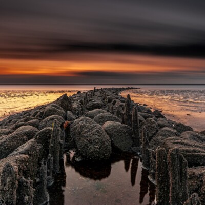 Dijk van stenen en palen in de zee